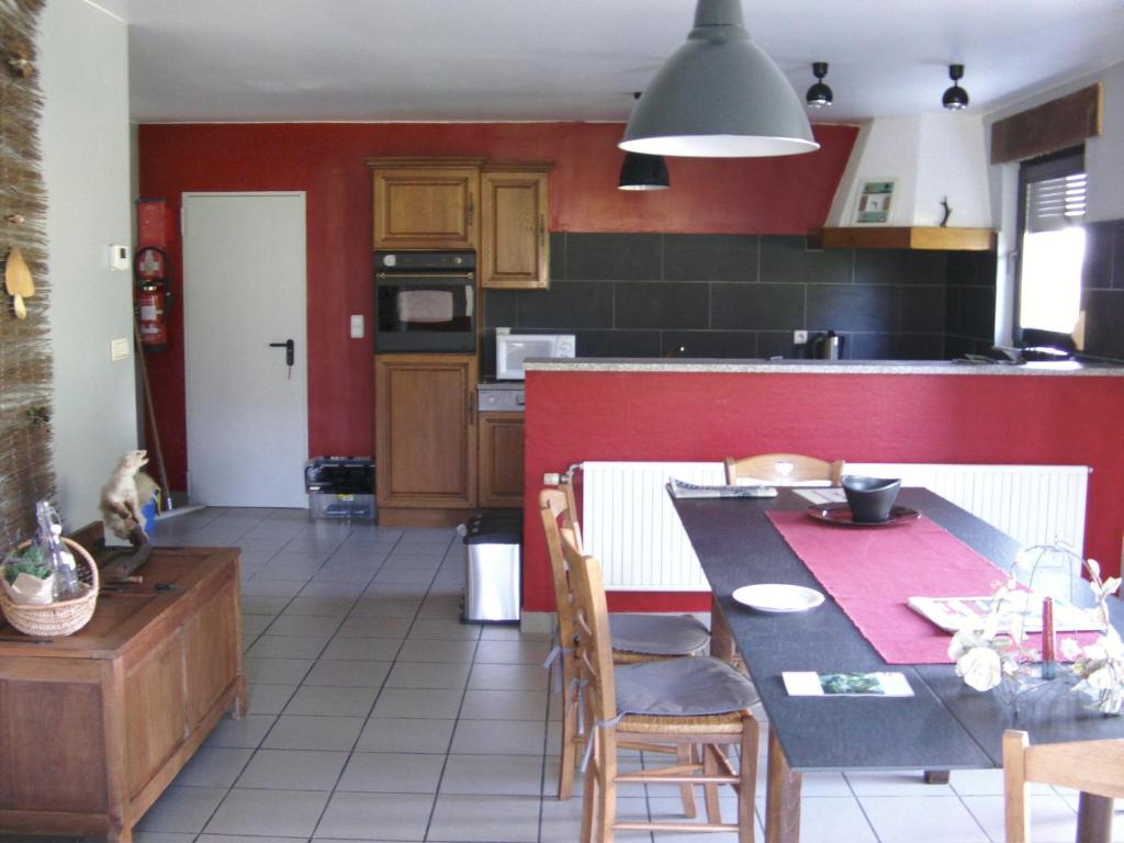 讷沙托Gîte Les Framboisiers的厨房配有桌子和红色的墙壁