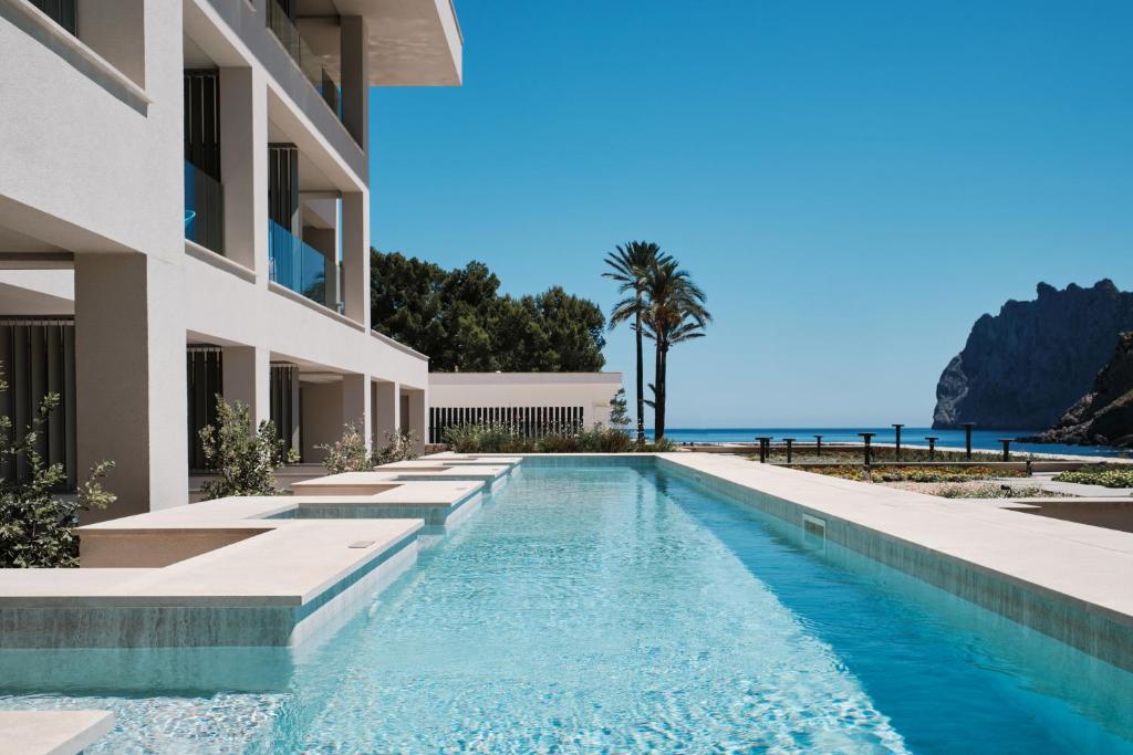 卡拉圣维森特El Vicenç de la Mar - Adults Only - Over 12的一座位于一座建筑前方的游泳池,背景是大海