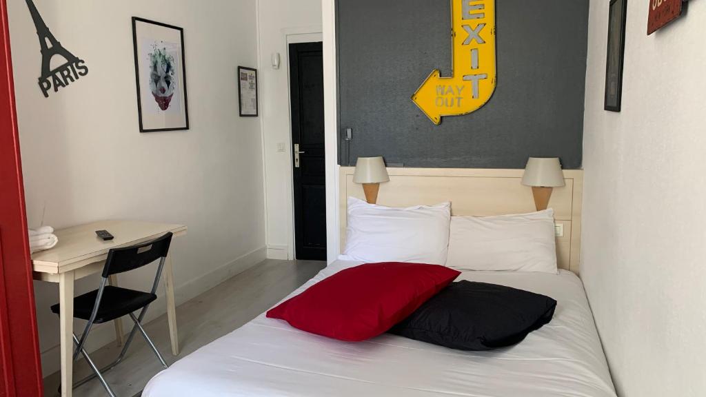 鲁昂Hotel centre Rouen的一间卧室配有一张带红色枕头的床和一张书桌