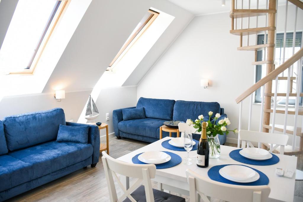 德布吉Apartamenty Wrzosowa的客厅配有蓝色的沙发、桌子和椅子