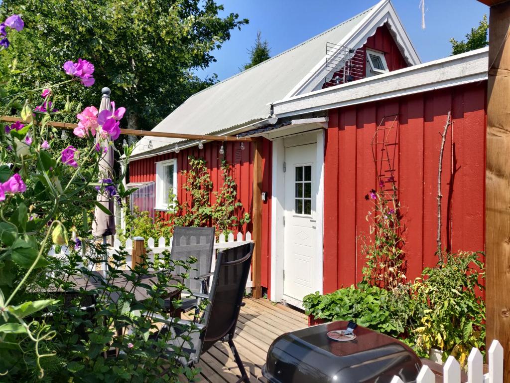 法尔肯贝里Lillstugan - Centralt och havsnära i lugnt villområde的红棚,有白色的门和鲜花