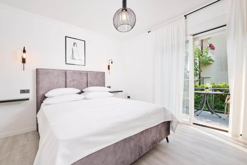 乌马格Royal Rei Suite的白色卧室设有一张大床和一个阳台