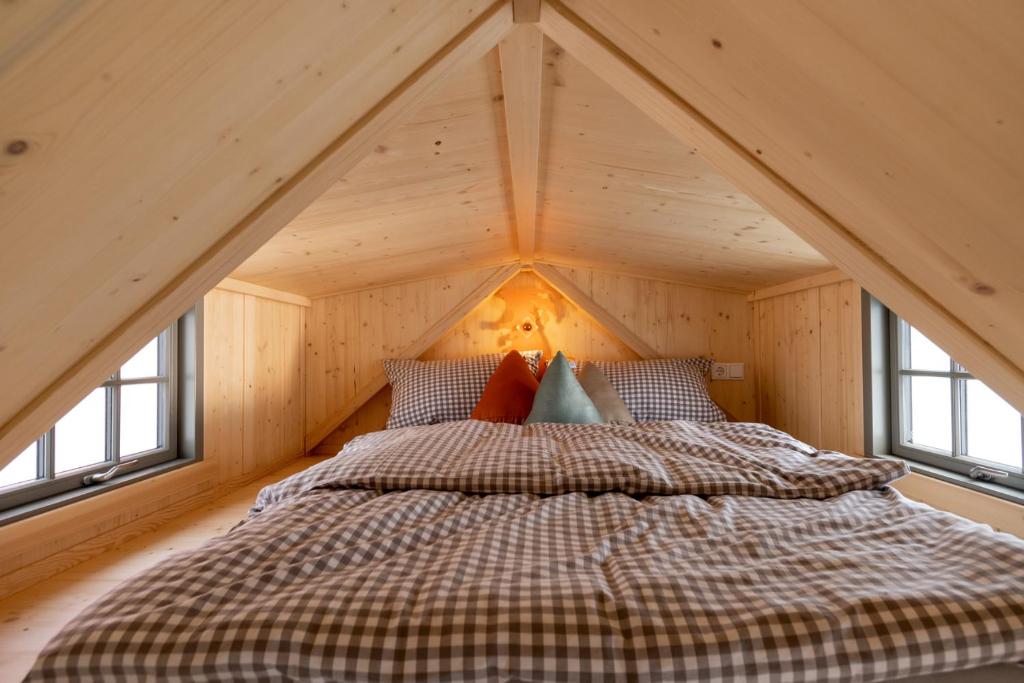 CaldenGrimmwald Tiny House的木制客房的一张床位,设有窗户