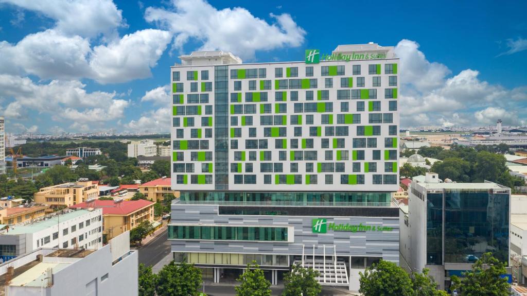 胡志明市Holiday Inn & Suites Saigon Airport, an IHG Hotel的一座高大的白色建筑,设有绿色的窗户