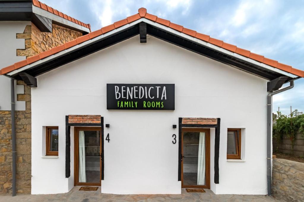 苏安塞斯BENEDICTA FAMILY ROOMS的白色的建筑,上面标有读过贝尼迪卡家庭间的标志