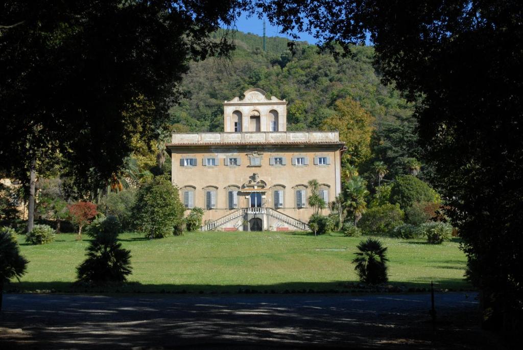 圣朱利亚诺-泰尔梅Villa di Corliano Relais all'Ussero的草场上树木繁茂的大建筑
