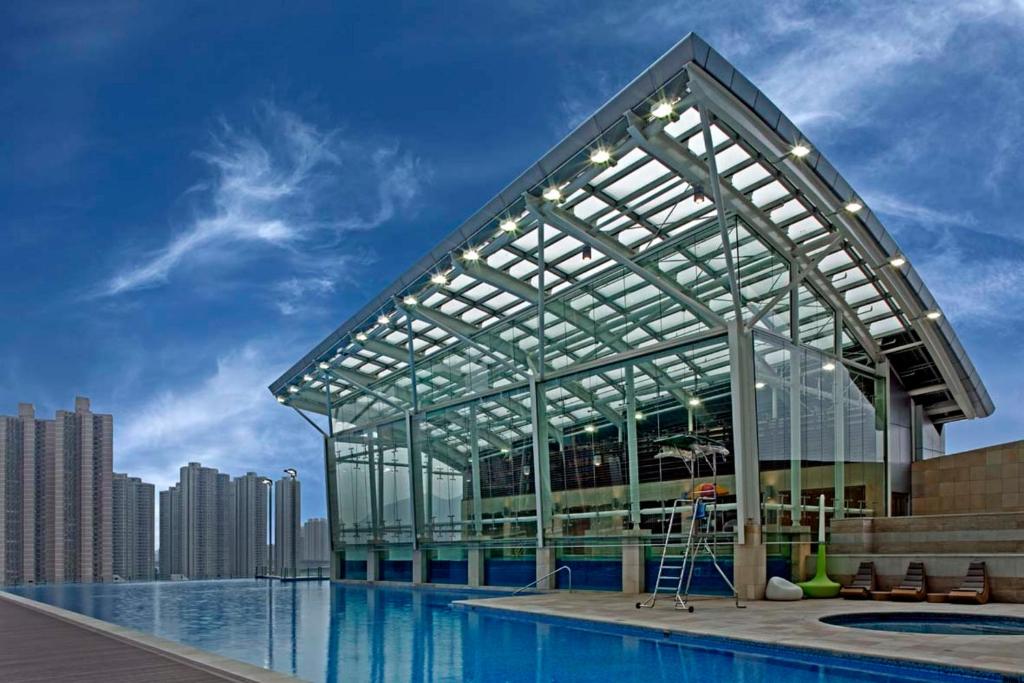 香港荃湾西如⼼酒店的一座大型玻璃建筑,毗邻游泳池