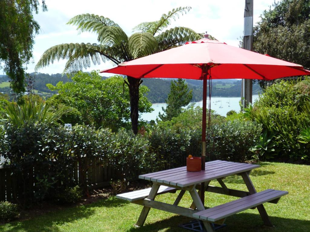 Opua奥普阿精品海景汽车旅馆 的一张带红伞和长凳的野餐桌