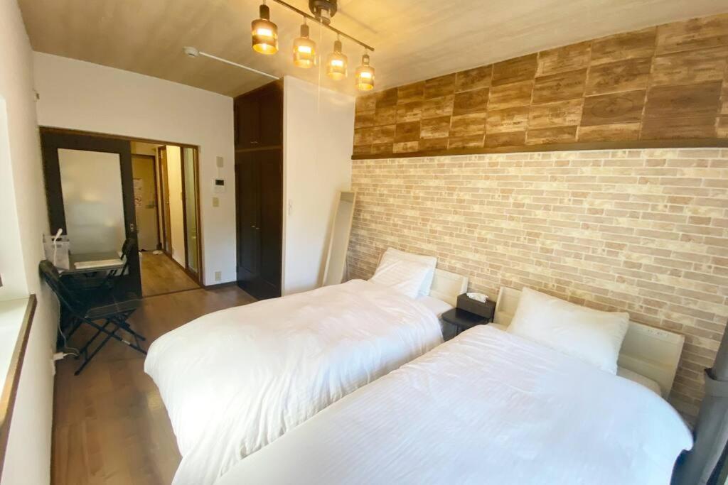 Shimeラ・ポート空港前107的一间卧室设有两张床和砖墙