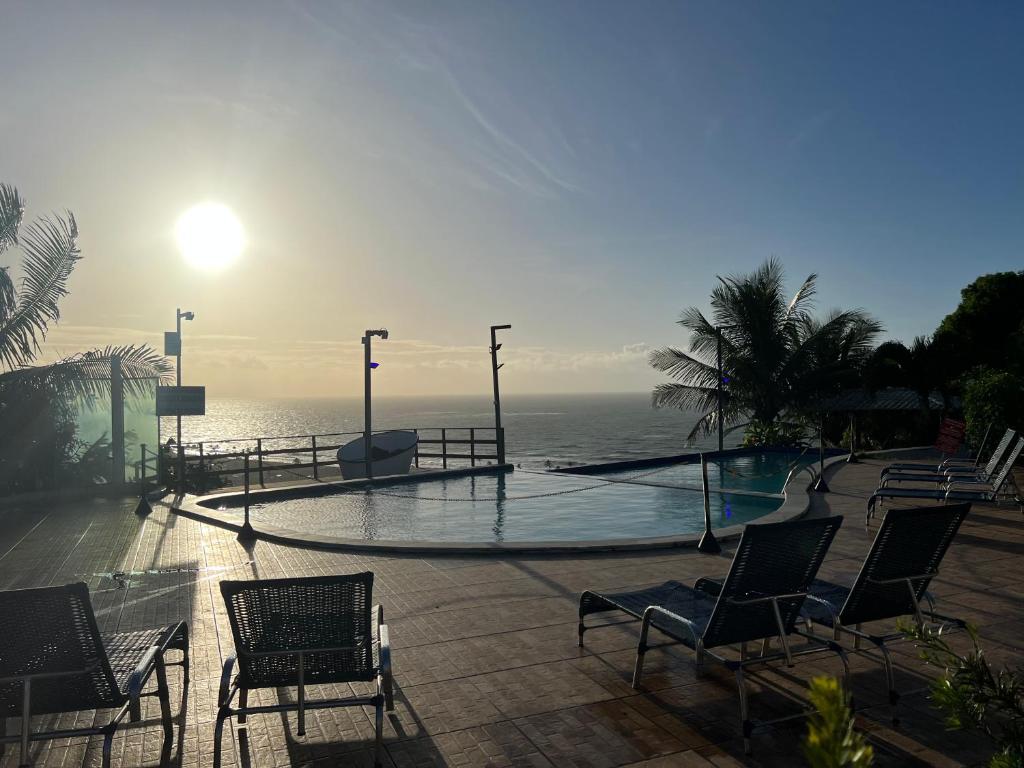 马塞约Pousada Paradise Vista do Atlantico的一个带椅子的游泳池,背景是大海