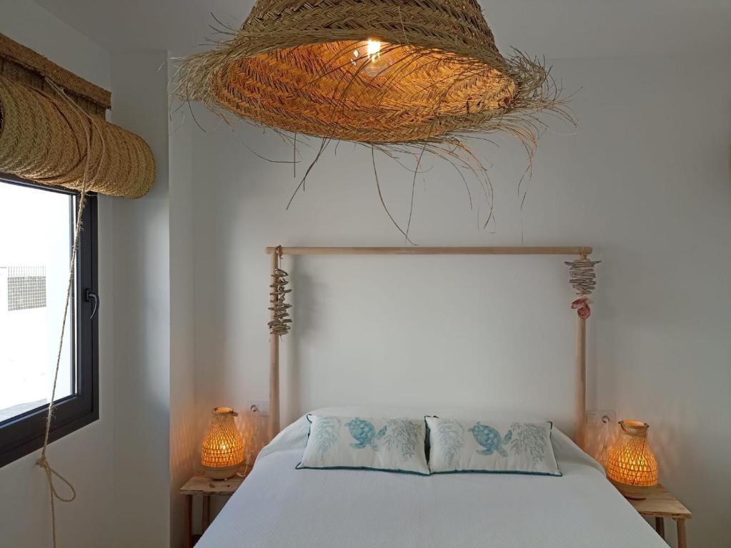科尼尔-德拉弗龙特拉Mirador de Trafalgar Conil的一间卧室配有一张床,天花板上挂着一个篮子