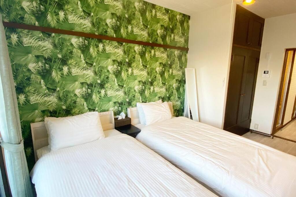 Shimeラ・ポート空港前101的卧室设有两张床铺和绿色的墙壁