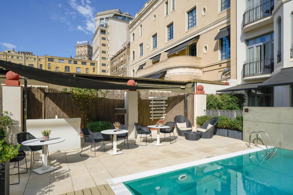 巴塞罗那加泰罗尼亚格拉西亚大道酒店的游泳池旁带桌椅的天井