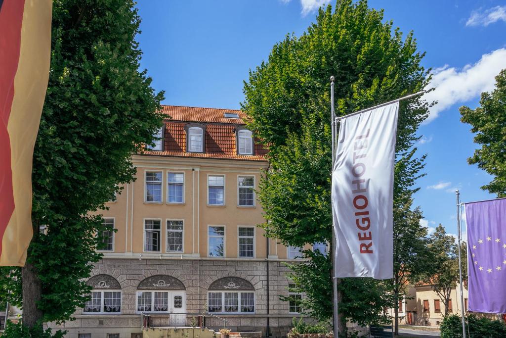 奎德林堡REGIOHOTEL Quedlinburger Hof Quedlinburg的前面有旗帜的建筑