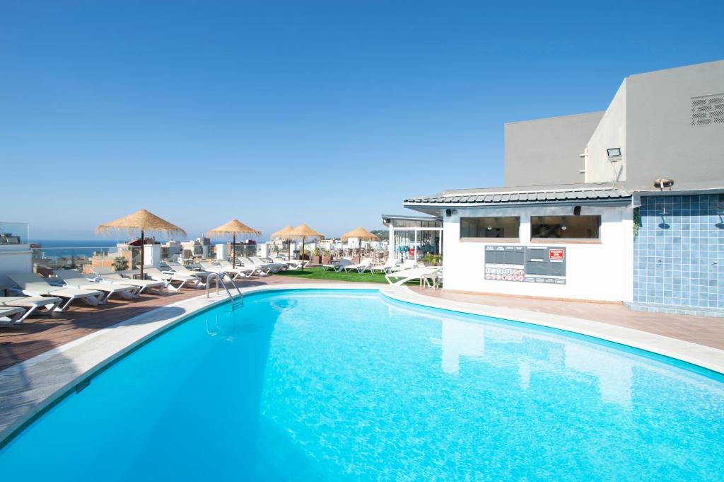 罗列特海岸Hotel Lloret Santa Rosa by Pierre & Vacances的一个带椅子的游泳池,背景是大海