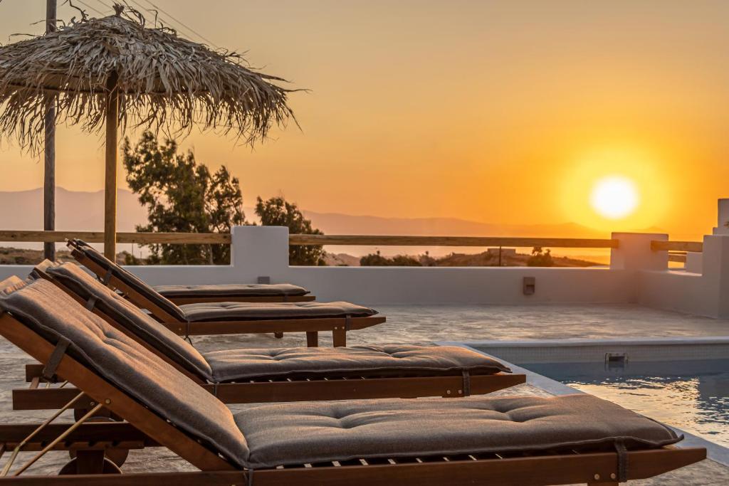 VívlosGolden Sand Villas with Private Pool的一组躺椅,坐在游泳池旁,欣赏日落美景
