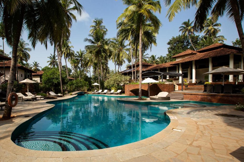 波戈马洛Coconut Creek Resort - Dabolim Airport的棕榈树度假村的游泳池