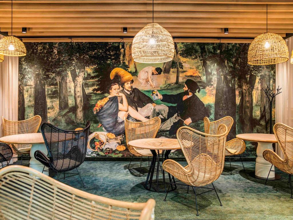 弗罗茨瓦夫弗罗茨瓦夫市中心美居酒店的餐厅内的壁画,配有桌椅