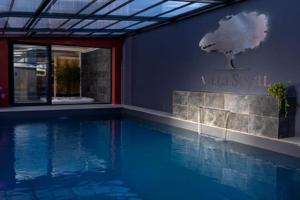 勒芒Villa Seyal - avec piscine - jacuzzi - sauna & climatisation的带有别墅咒语标志的游泳池