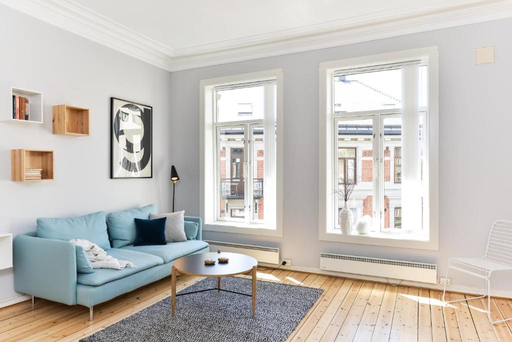 奥斯陆奥斯陆皇家公园奥卢弗雷蒙服务式公寓的客厅设有蓝色的沙发和2扇窗户。