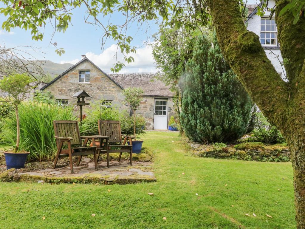 洛亨黑德Inglis Nook Cottage的房屋前设有带2把椅子和1张桌子的花园