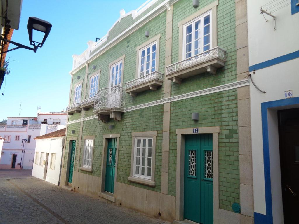 奥德赛克斯AL-Odeceixe Verde的绿色砖砌建筑,设有白色窗户和绿色门