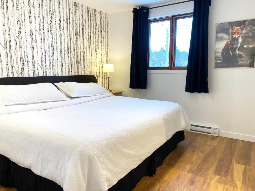 Saint-Férréol-les-Neiges蒙莫朗西山林小居的卧室设有一张白色大床和一扇窗户。