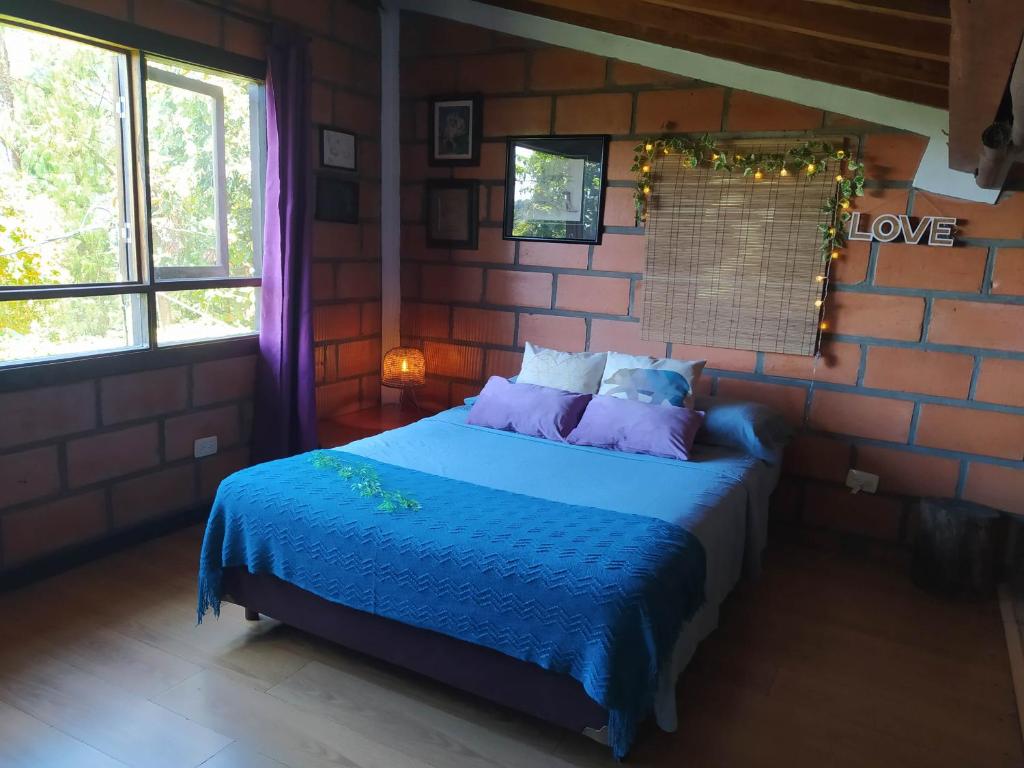 圣埃伦娜Refugio en las Nubes的一间设有蓝色床的砖墙卧室