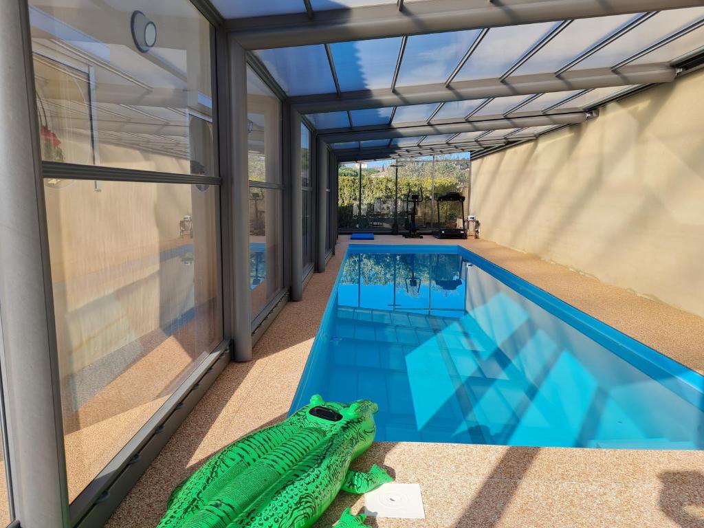 BizanetChambres d'hôtes B&B La Bergeronnette avec piscine couverte chauffée的一座房子旁的游泳池,里面设有乌龟玩具