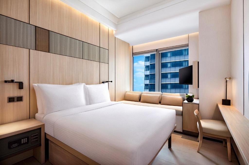 上海大都会海逸酒店的卧室配有一张白色的大床和一张沙发。