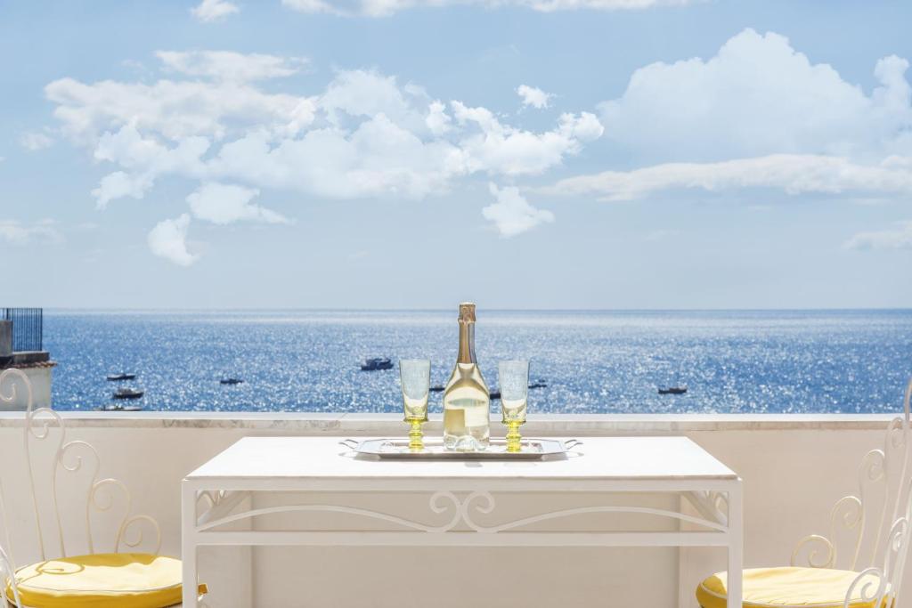 波西塔诺弗拉维奥焦亚别墅酒店的一张带一瓶葡萄酒和眼镜的白色桌子