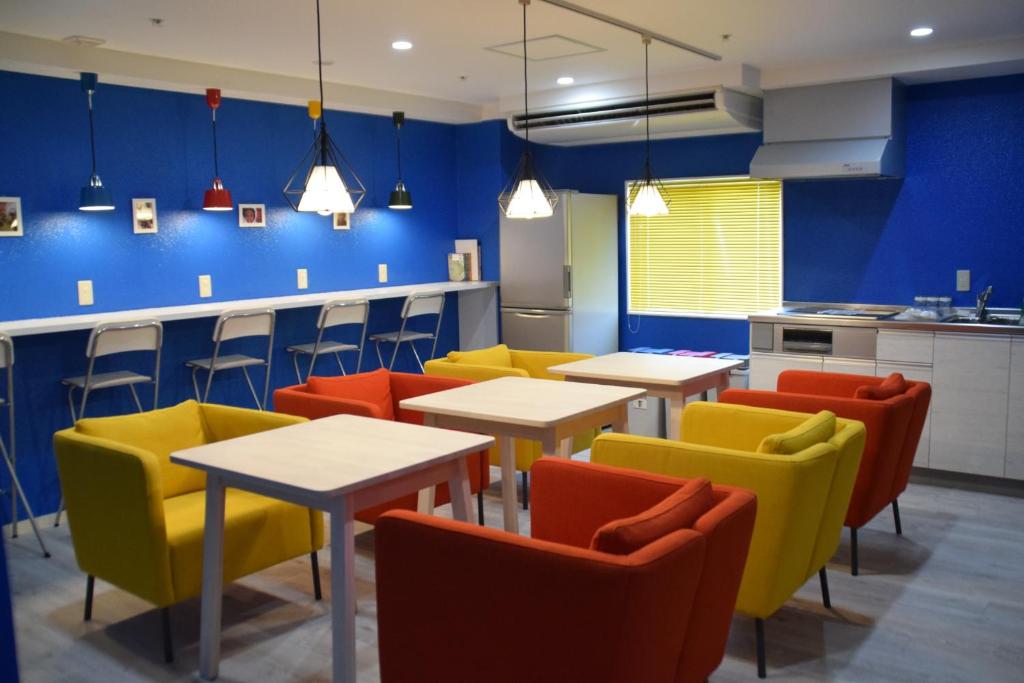 神户安克雷奇旅舍的餐厅设有桌椅和蓝色的墙壁