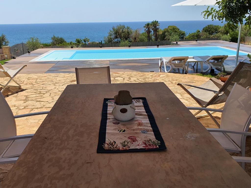 托雷瓦多Villa Pozzo Pasulo的坐在泳池旁木桌边的帽子