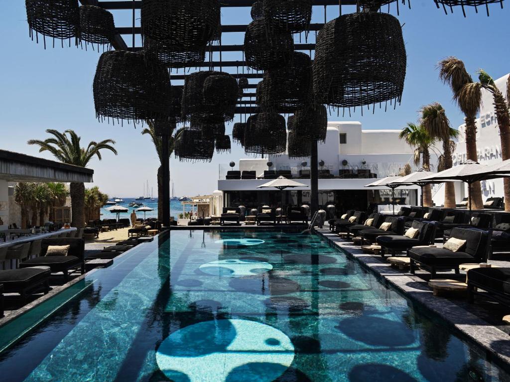奥诺斯Myconian O, a Member of Design Hotels的一个带椅子的游泳池,一个度假胜地