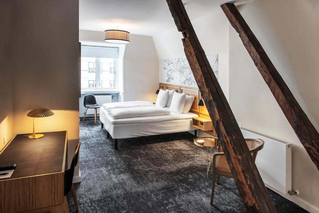 霍森斯Jørgensens Hotel的配有一张床和一张书桌的酒店客房