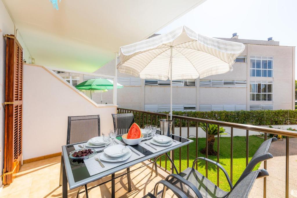 阿尔库迪亚Es Pujol的阳台配有桌椅和遮阳伞。