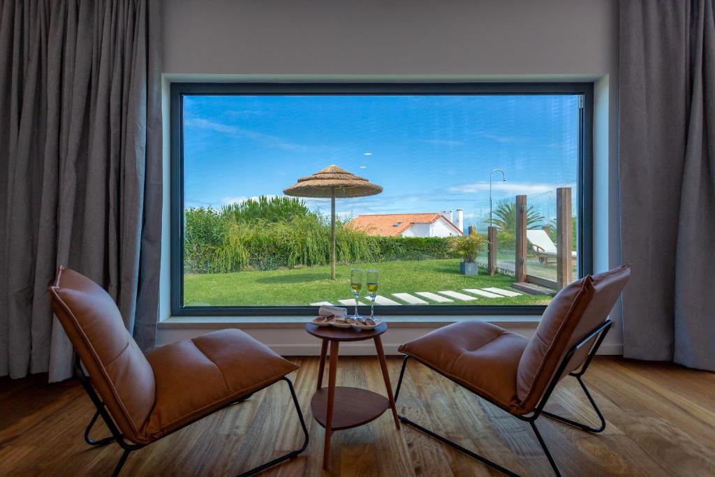 科拉雷斯BeGuest SunRoca Suites的客厅配有两把椅子和大窗户