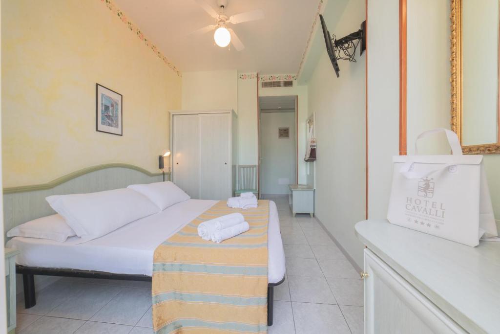 卡托利卡Hotel Cavalli的一间卧室配有一张床和一张桌子,上面配有毛巾
