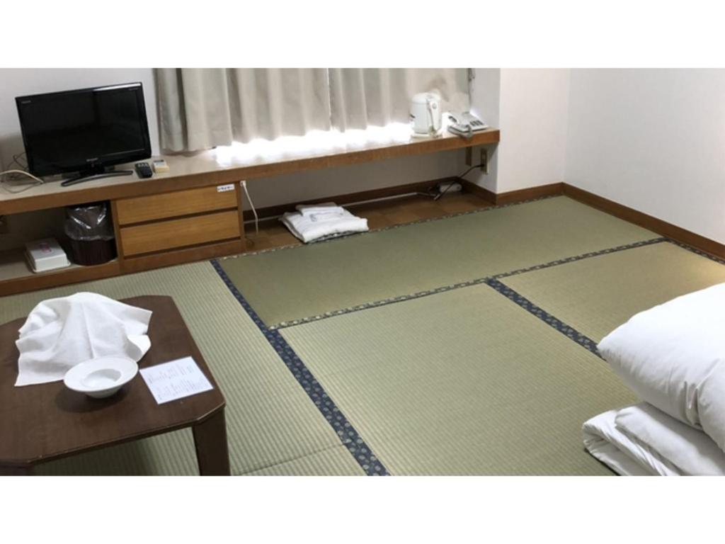 静冈Kagetsu Ryokan - Vacation STAY 04023v的酒店客房设有床、桌子和电视。