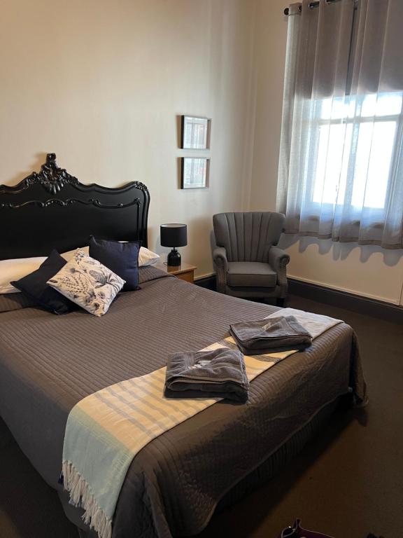 蒂默特Oriental Hotel Tumut的一间卧室配有一张带椅子的床和一扇窗户