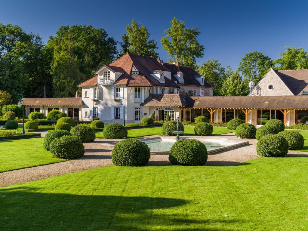 勒韦尔努瓦德乐伟诺酒店的一座白色的大房子,有一座灌木丛的院子