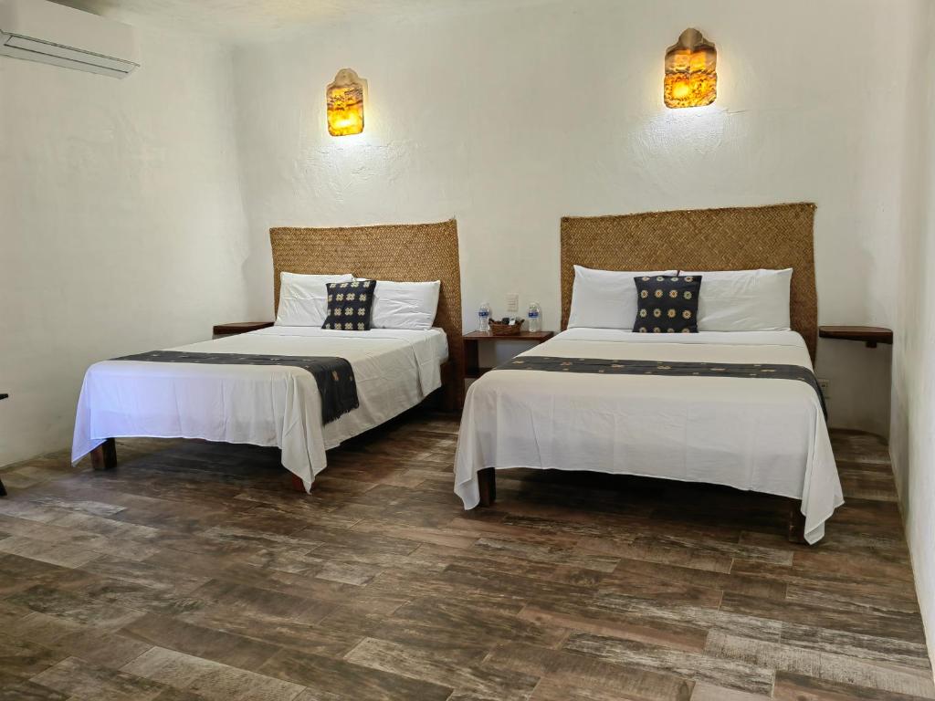 萨尤利塔VILLA DEL PEZ的客房设有2张带白色床单和灯具的床。