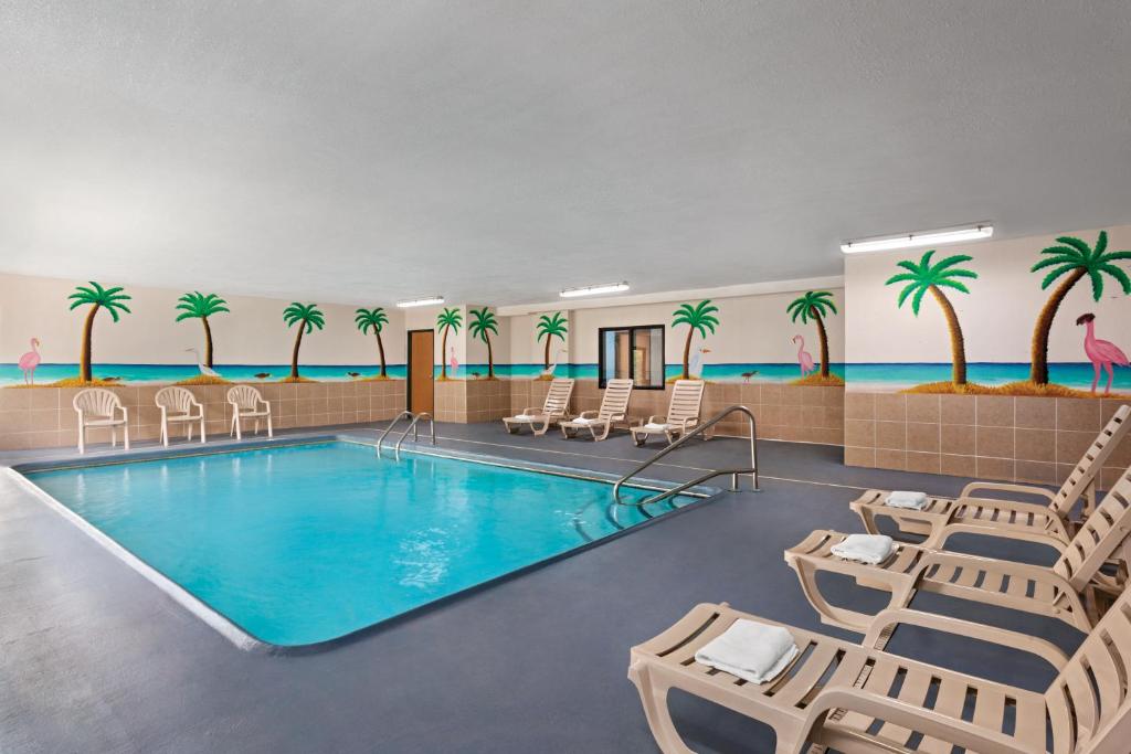 堪萨斯城堪萨斯城国际机场戴斯酒店的墙上的游泳池,配有椅子和棕榈树