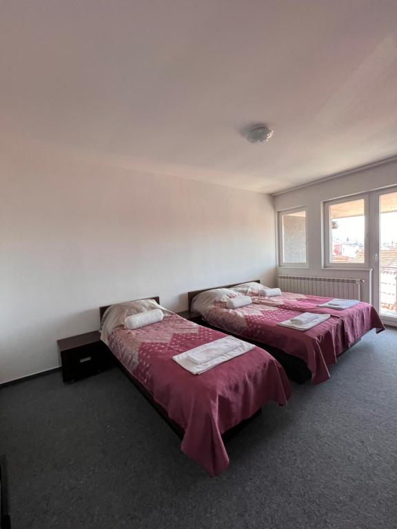 萨拉热窝Hotel Begić的红色床单的客房内的两张床