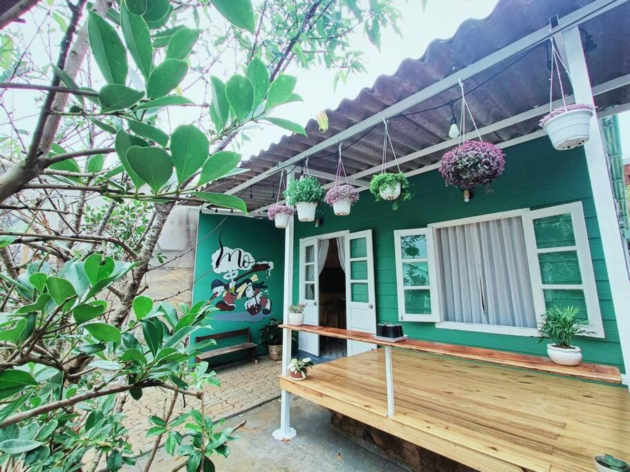 大叻MOre Home - Ngôi nhà nghĩ dưỡng tại Đà Lạt的一座绿色房子,前面设有木甲板