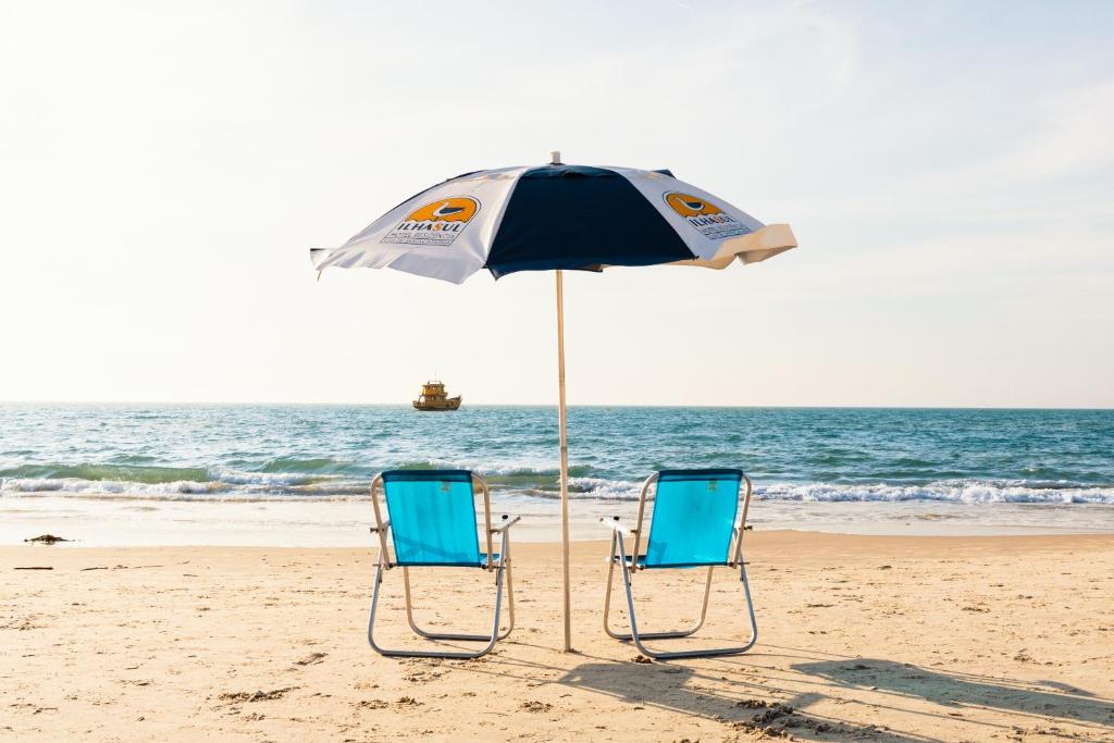 弗洛里亚诺波利斯Ilhasul Hotel Residencia的海滩上的两把椅子和一把遮阳伞