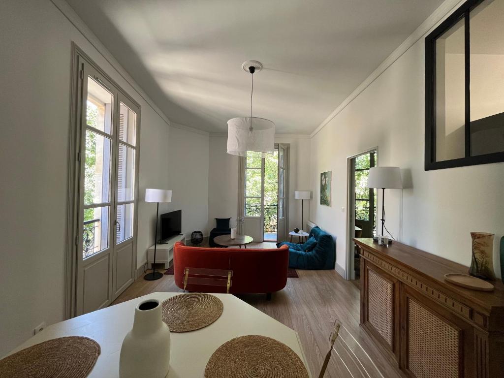 尼姆Nimes , appartement rénové dans immeuble classé.的客厅配有桌子和红色椅子
