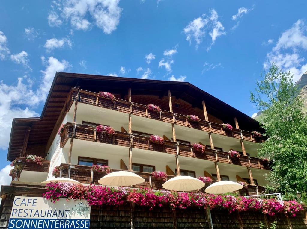 皮茨河谷圣莱昂哈德Hotel Zirbenhof的一座建筑,上面有雨伞和鲜花