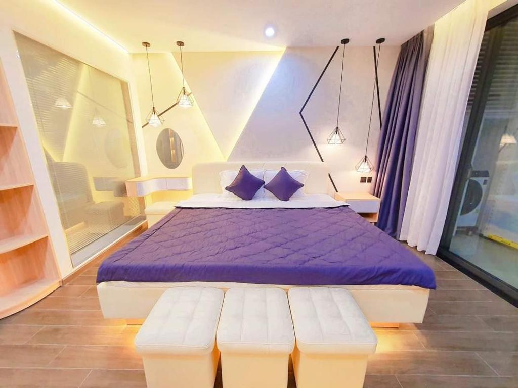 莲三Apec Sunsea Condotel Phu Yen的一间卧室配有一张带紫色床单和蓝色枕头的床。