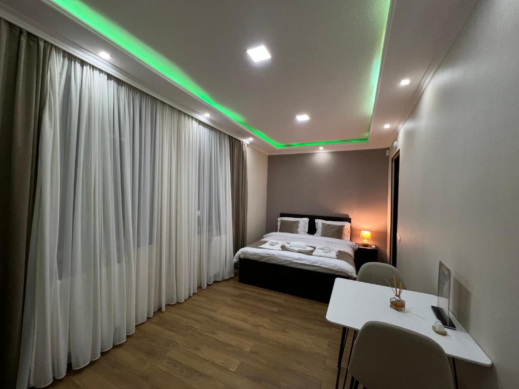 博尔若米Serenity Likani Villa Hotel的一间卧室配有一张带绿灯的天花板床。